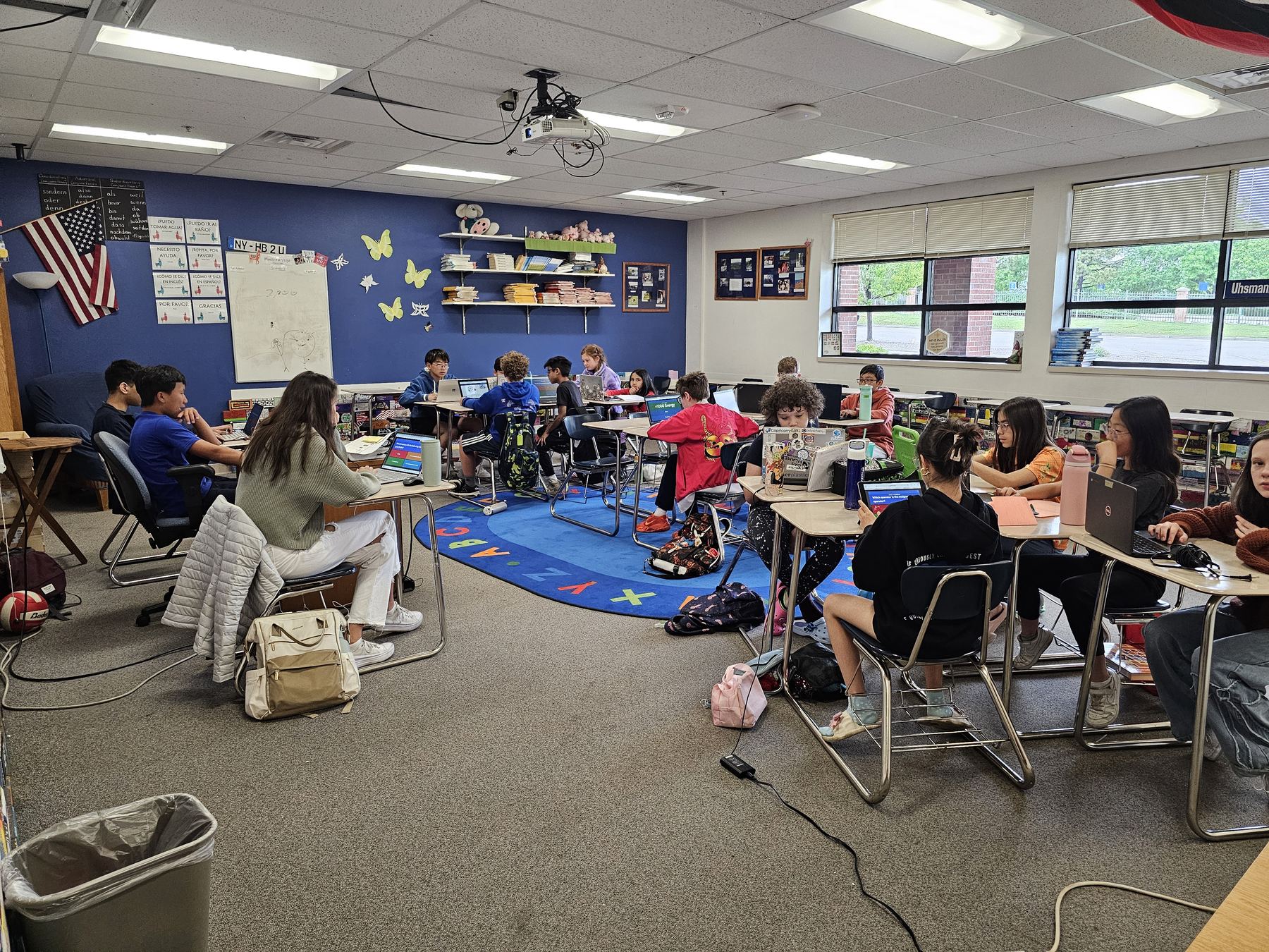 A full classroom of students at laptops during a Steel City Codes chapter, with a mentor working one-on-one at the front table.